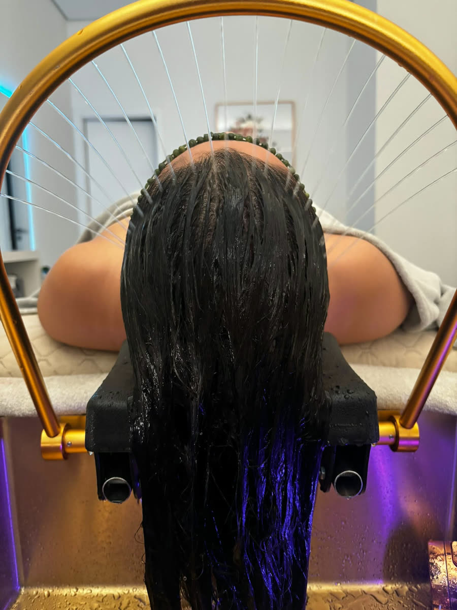Cascata de água morna sobre o cabelo, na cuba dourada do head spa